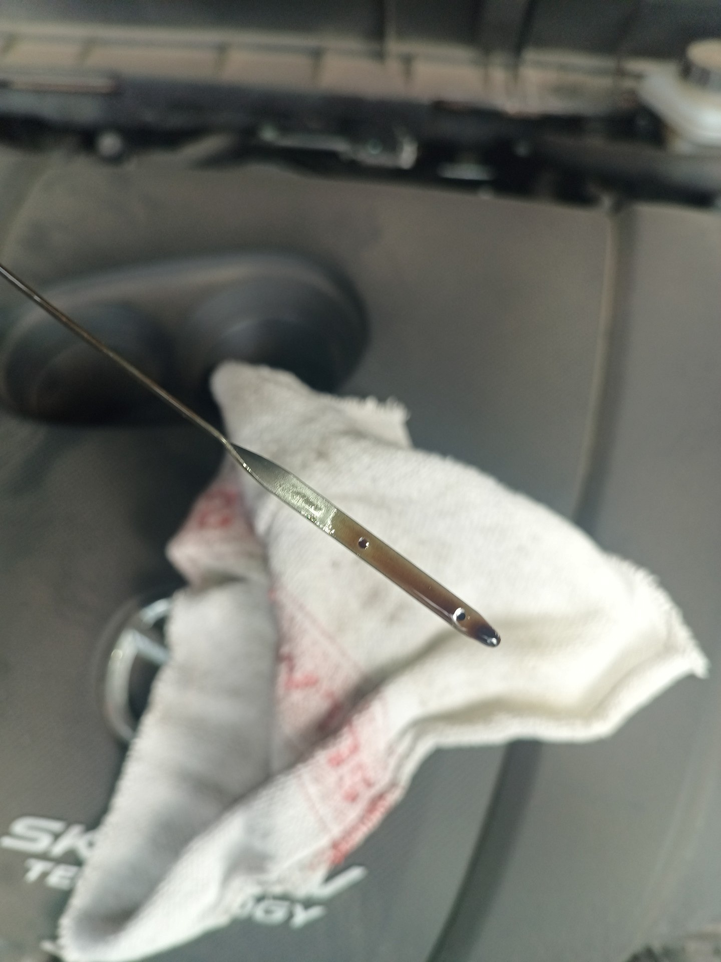 Końcówka bagnetu oleju silnikowego Mazdy CX-3 nad jasną szmatką